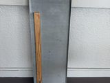 a large metal mirror with a wooden handle next to a white wall