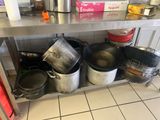 de nombreuses casseroles et poêles posées sur une étagère dans la cuisine