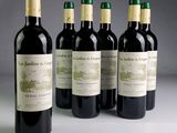 four bottles of red wine are lined up on a table