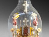 a small glass bottle with a miniature house inside of it