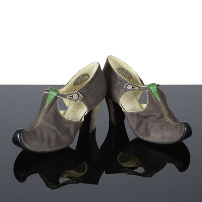 une paire de chaussures pour femme posée sur une surface réfléchissante, sur fond blanc