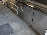une cuisine équipée de plans de travail en inox et d'un réfrigérateur en inox