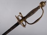 un gros plan d'une épée avec une poignée en métal sur fond blanc