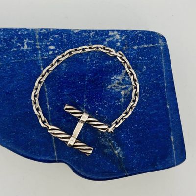 a close up of a bracelet with a cross on it on a blue stone