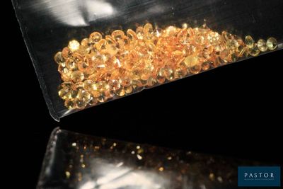 un sachet de perles dorées posé sur une surface noire