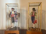 deux figurines représentant des hommes, exposées dans des vitrines posées sur une commode