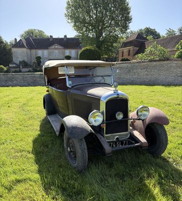 une vieille voiture garée dans l'herbe devant une maison