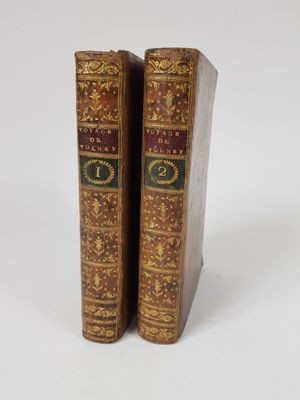two old books are sitting side by side on a white surface