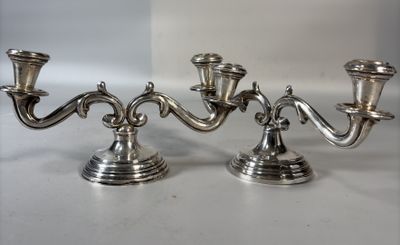 une paire de bougeoirs argentés posés sur une surface blanche