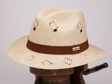 un chapeau de paille orné d'un ruban en cuir, posé sur un porte-chapeaux