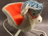 un petit cheval à bascule aux cheveux bleus et à la selle rouge