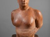 une sculpture représentant le buste d'une femme, posée sur une table en bois