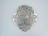 a silver broochee on the wall of a bathroom
