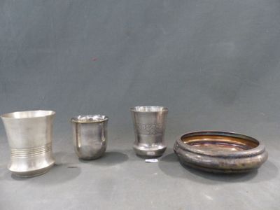 trois tasses en argent et un bol posés sur une table