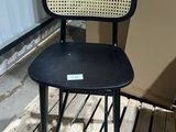 a black chair with a wicker back and seat on a wooden floor