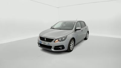 La voiture argentée est garée dans une pièce blanche au sol blanc.