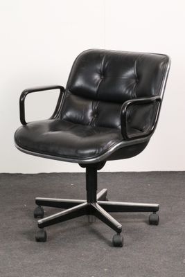 une photo d'une chaise de bureau en cuir noir à roulettes posée sur un sol recouvert de moquette