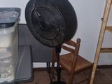 a fan that is sitting on a table next to a chair