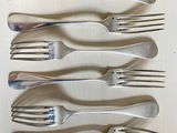 six forks are lined up in a row on a table