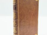 a brown book with gold trim sitting on top of a white surface