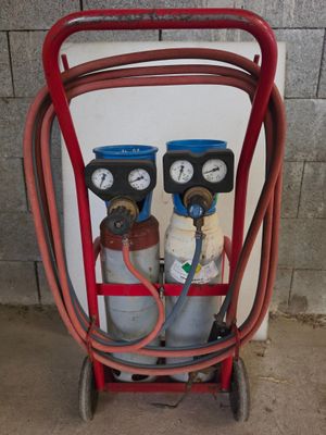 deux bouteilles de gaz posées sur un chariot, reliées par un tuyau