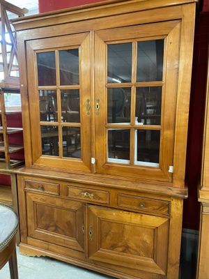 un vaisselier en bois avec des portes vitrées et une chaise