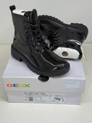 pair of black boots on a white box with a phone in it