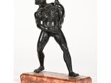 une statue en bronze représentant un homme tenant un sac, posée sur un socle en marbre