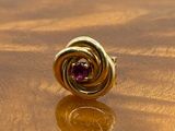 a gold ring with a purple stone on a wooden table