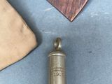 a small metal object on a table next to a piece of wood