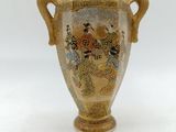 a gold vase with a painting on it on a white surface