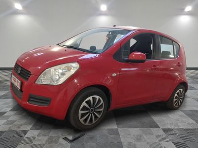 une voiture rouge est garée dans une pièce au sol en damier