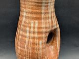 un vase marron troué sur fond noir