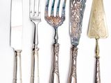 quatre fourchettes, un couteau et une cuillère posés sur un plan de travail blanc