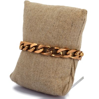 gros plan d'un bracelet en chaîne en or sur un oreiller
