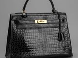 un sac à main en cuir de crocodile noir avec des finitions dorées