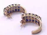 pair of gold and blue sapphire earrings on a white surface