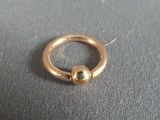 a gold ring with a bead on it on a table