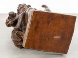 a wooden sculpture of a woman laying down on the ground