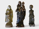 three figurines of a woman holding a child and a man holding a child