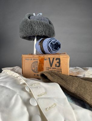 a pile of clothes and a pair of gloves on top of a bed