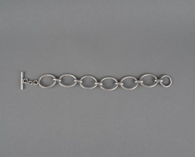 un gros plan d'un bracelet en argent posé sur une surface grise