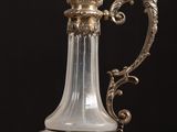 a glass vase with a metal handle on a table