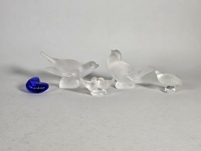 plusieurs oiseaux en verre posés sur une table, à côté d'un œuf bleu