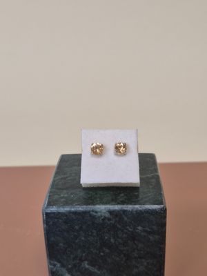 un gros plan sur une paire de boucles d'oreilles en or posées sur un bloc de marbre