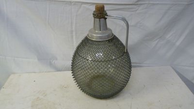 a glass bottle with a metal handle on a table