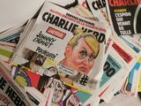 a pile of newspapers sitting on the floor next to a phone