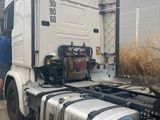 a truck that is parked in a lot with a man standing next to it