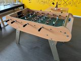 a foosball table in the middle of a room with a piano in the background