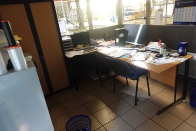 un bureau équipé de deux ordinateurs et d'un réfrigérateur dans une pièce